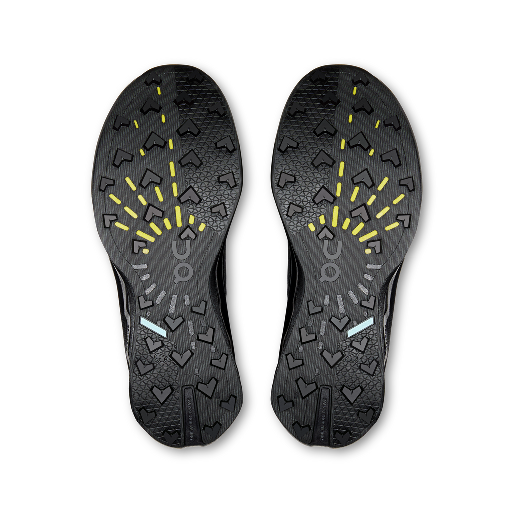 Women's black shoe outsole with patterned tread and bright yellow traction markings