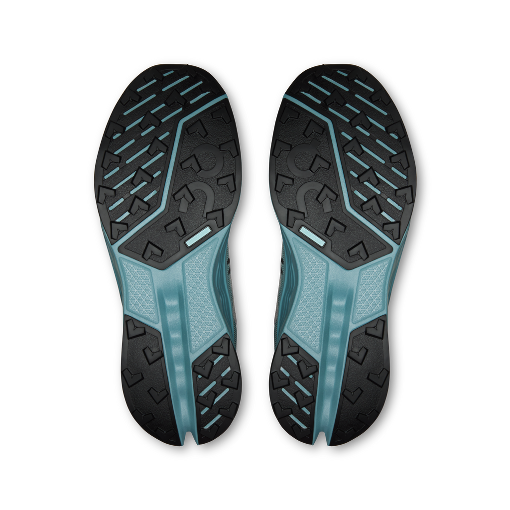Trail running shoe outsoles with rugged tread and teal rubber forefoot.