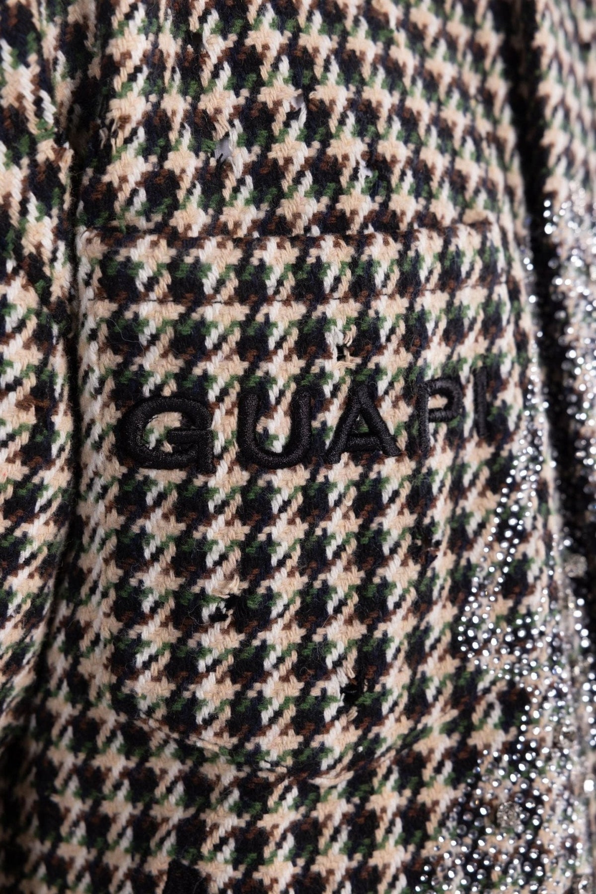 Close-up of houndstooth shirt logo text embroidery near rhinestone trim
