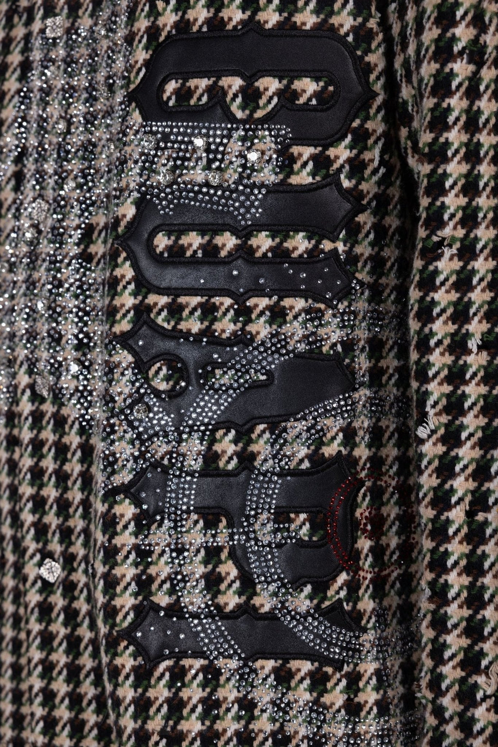 Close-up of black graphic patches with silver rhinestones on houndstooth shirt