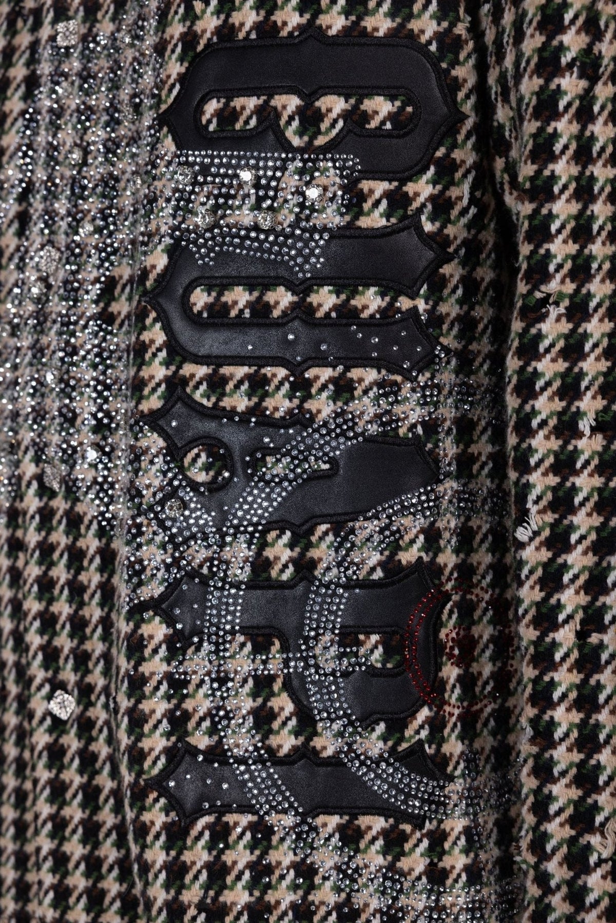 Close-up of black graphic patches with silver rhinestones on houndstooth shirt