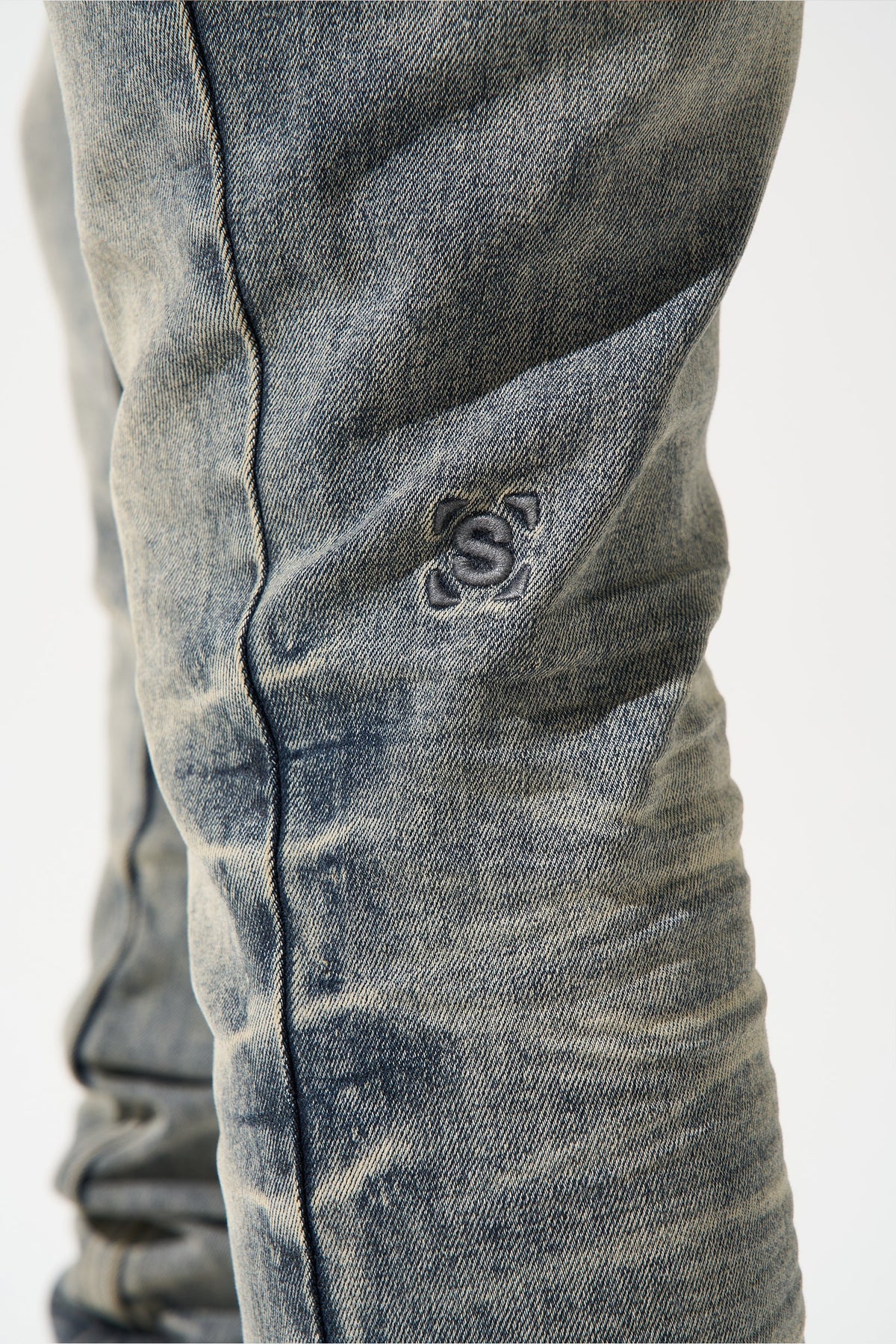Men's gunmetal jeans leg with contrast logo patch and vertical seam stitching