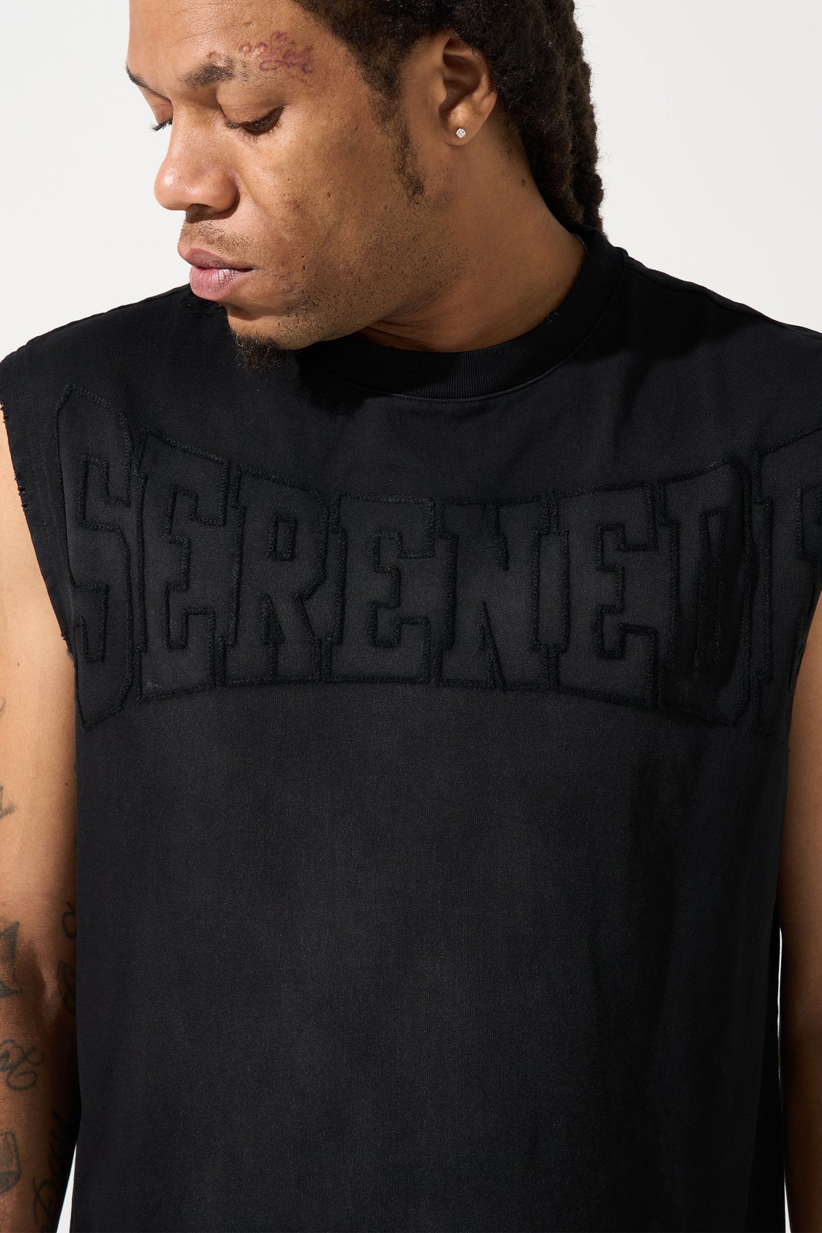 Men's black tank top close-up of raised SERENE logo on chest