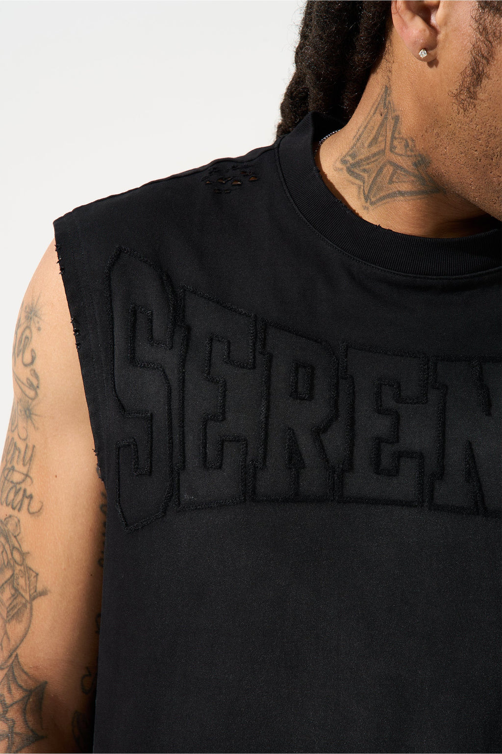 Men's black tank top close-up of raised SERENE logo and crew neckline