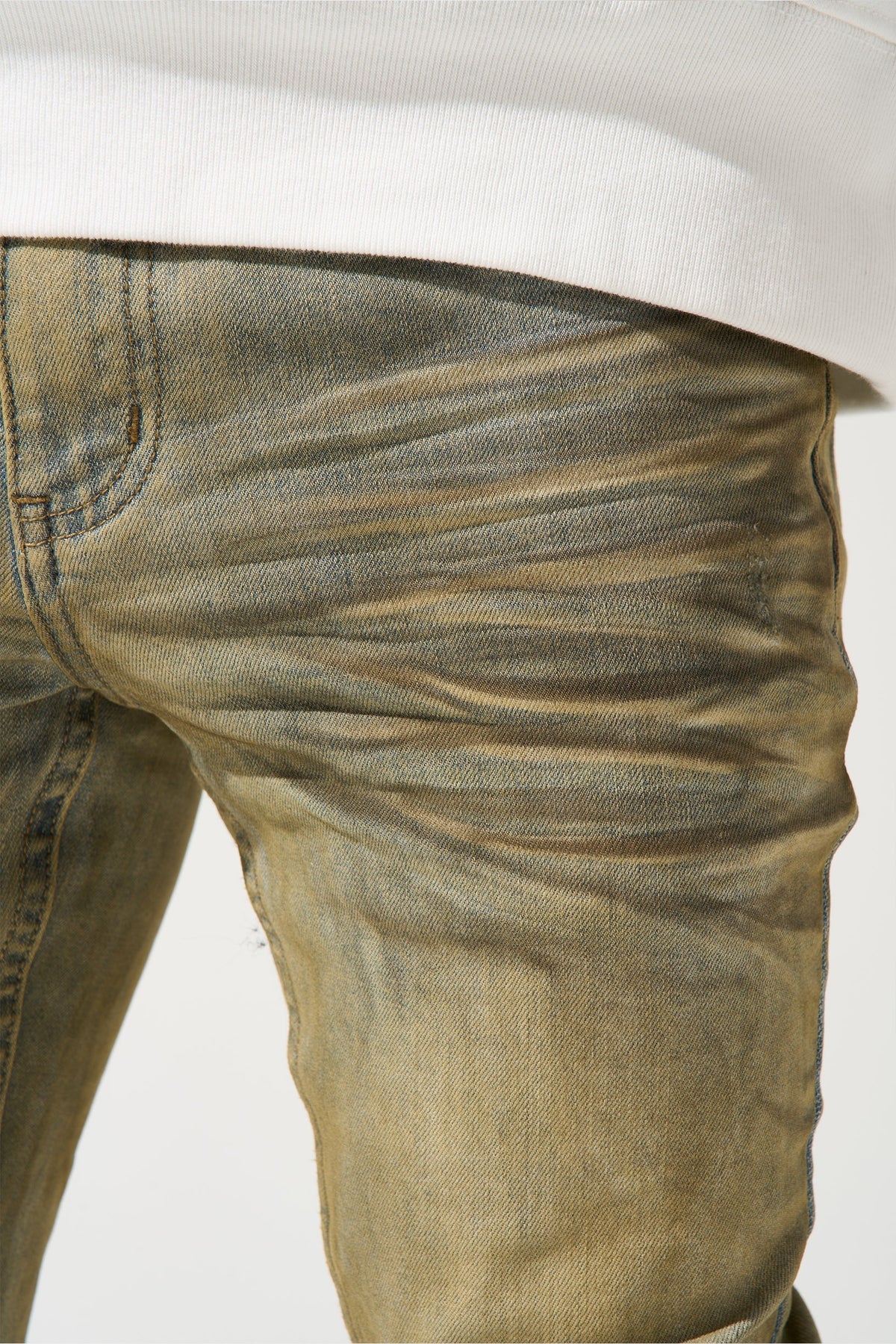 Close-up of men's muted olive jeans fabric with faded dirty wash and side seam detail