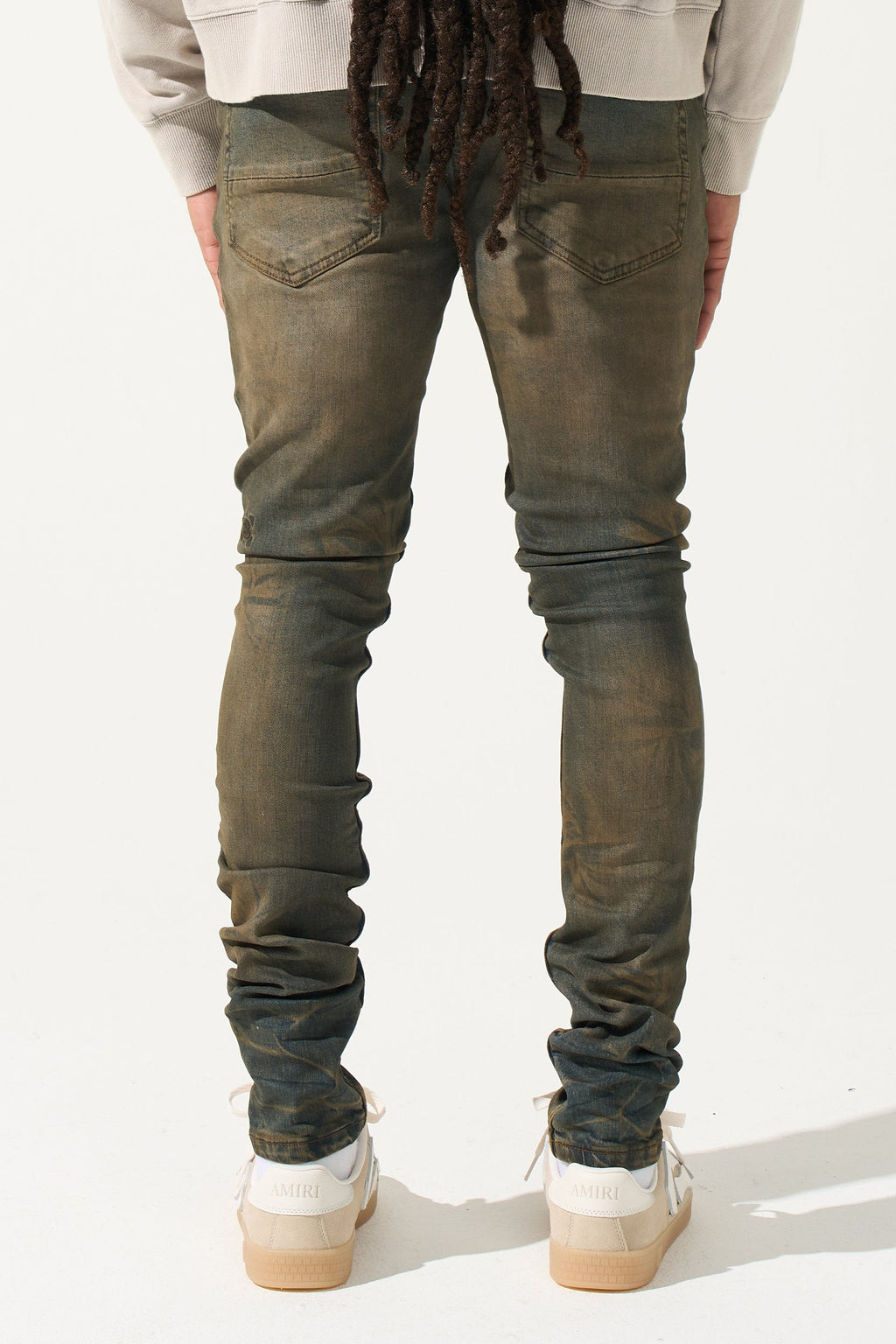 Earth-brown men's slim jeans with rear pockets and ruched leg creases.