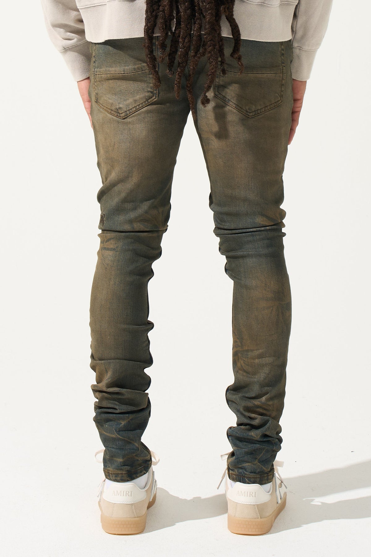 Earth-brown men's slim jeans with rear pockets and ruched leg creases.