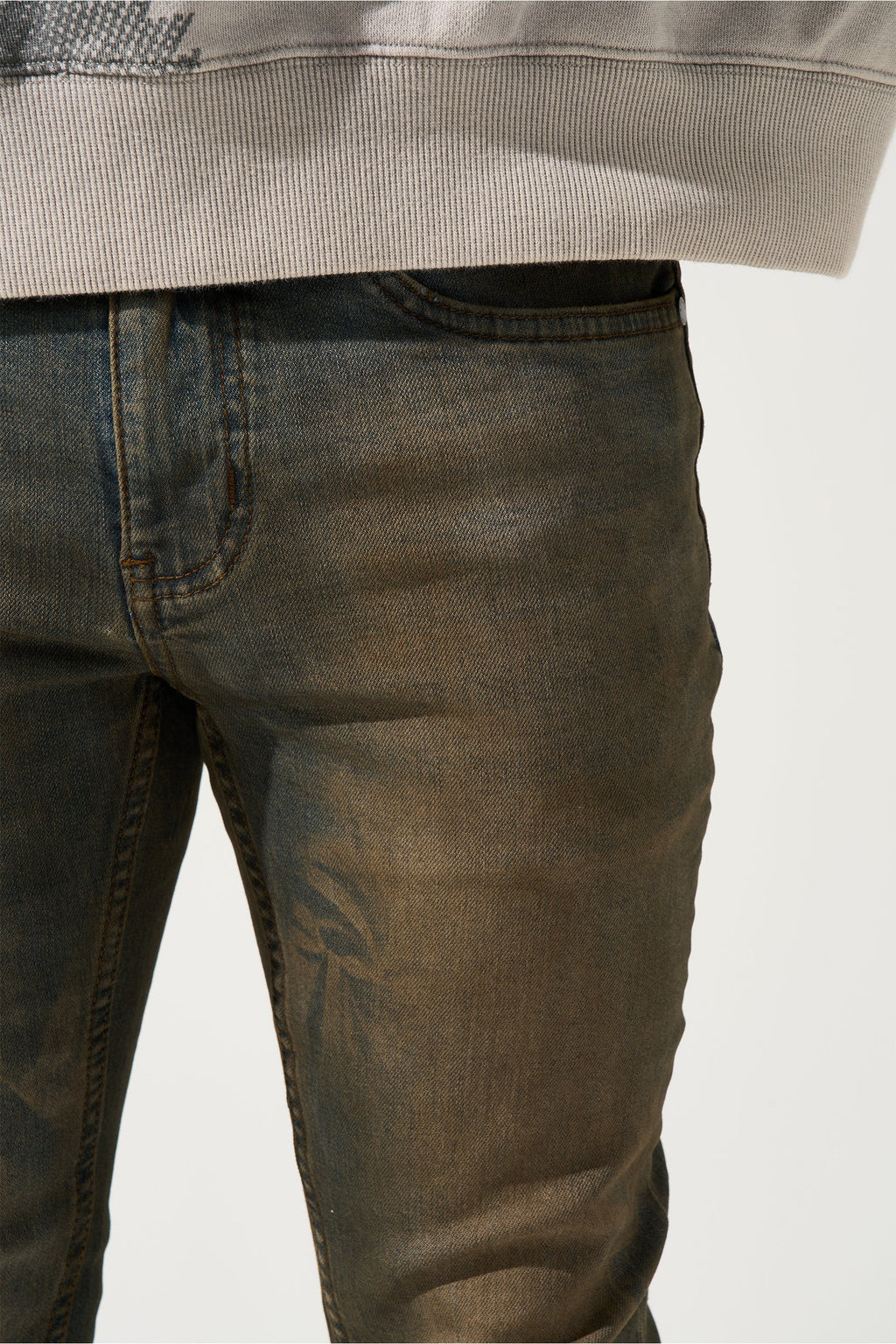 Earth-brown denim jeans close-up of waistband and topstitching.