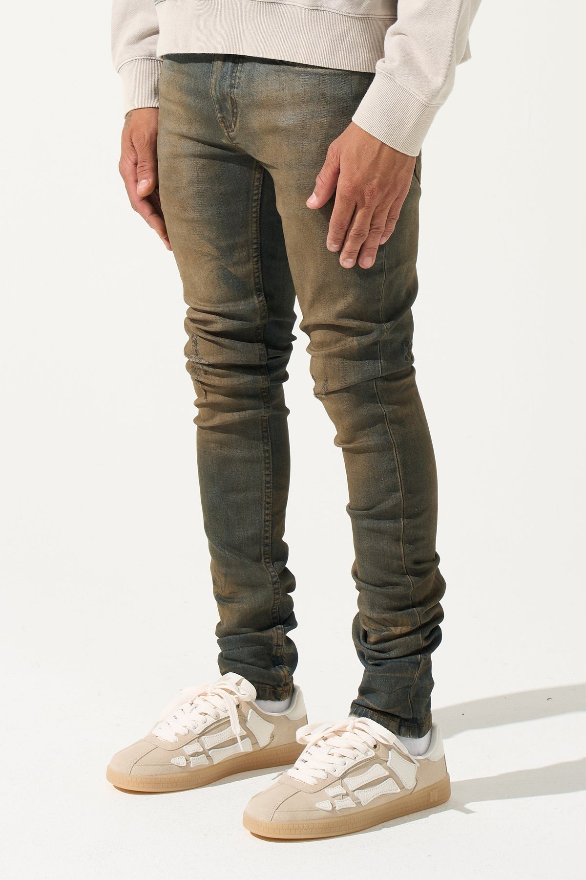Earth-brown men's slim jeans with ruched leg panels and tapered fit.