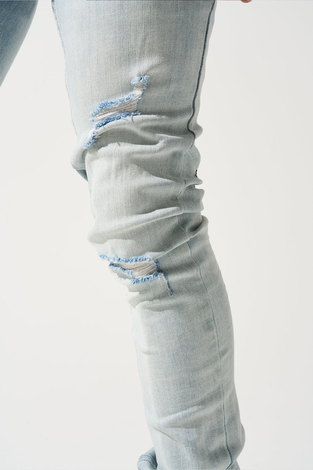 Light blue jeans with frayed knee rips and light wash fading on thighs