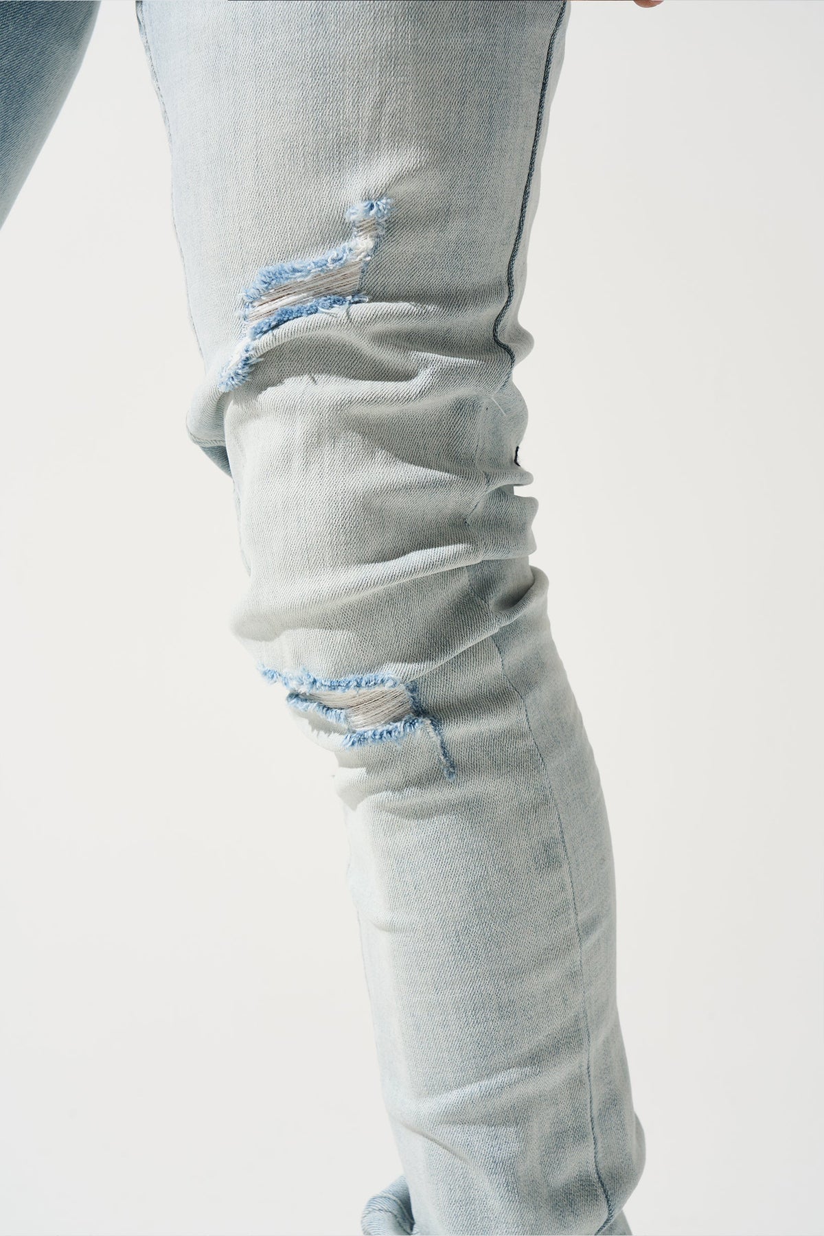 Light blue jeans with frayed knee rips and light wash fading on thighs
