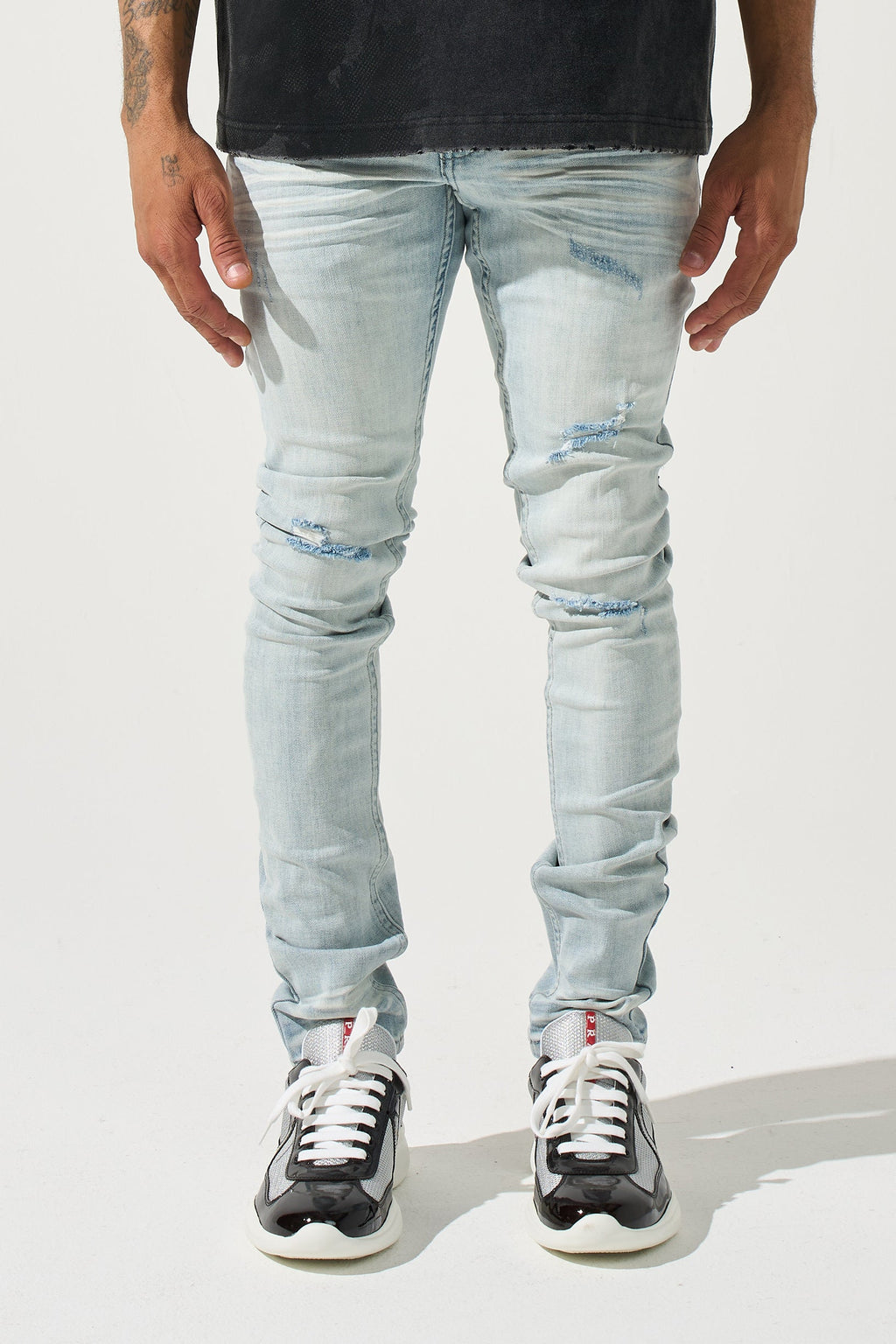 Light blue slim men’s jeans with ripped and faded details at knees and thighs