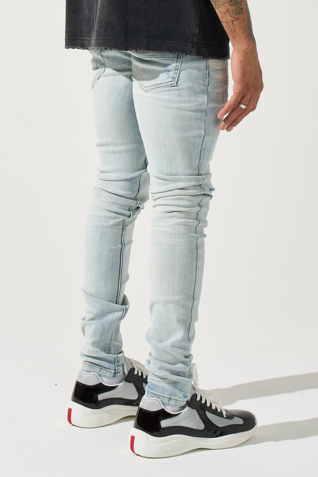 Light blue washed men’s jeans with multiple rips and knee seam distress