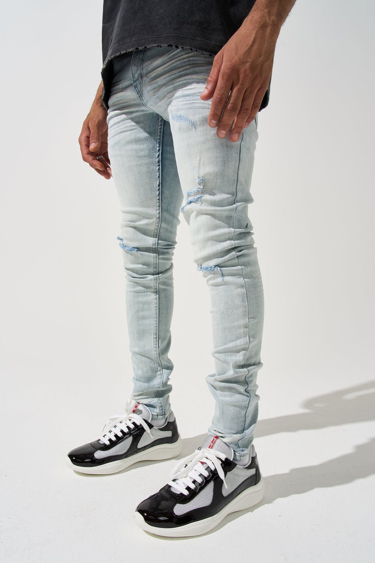 Light blue distressed men’s jeans, slim fit with faded panels and stitched knee rips