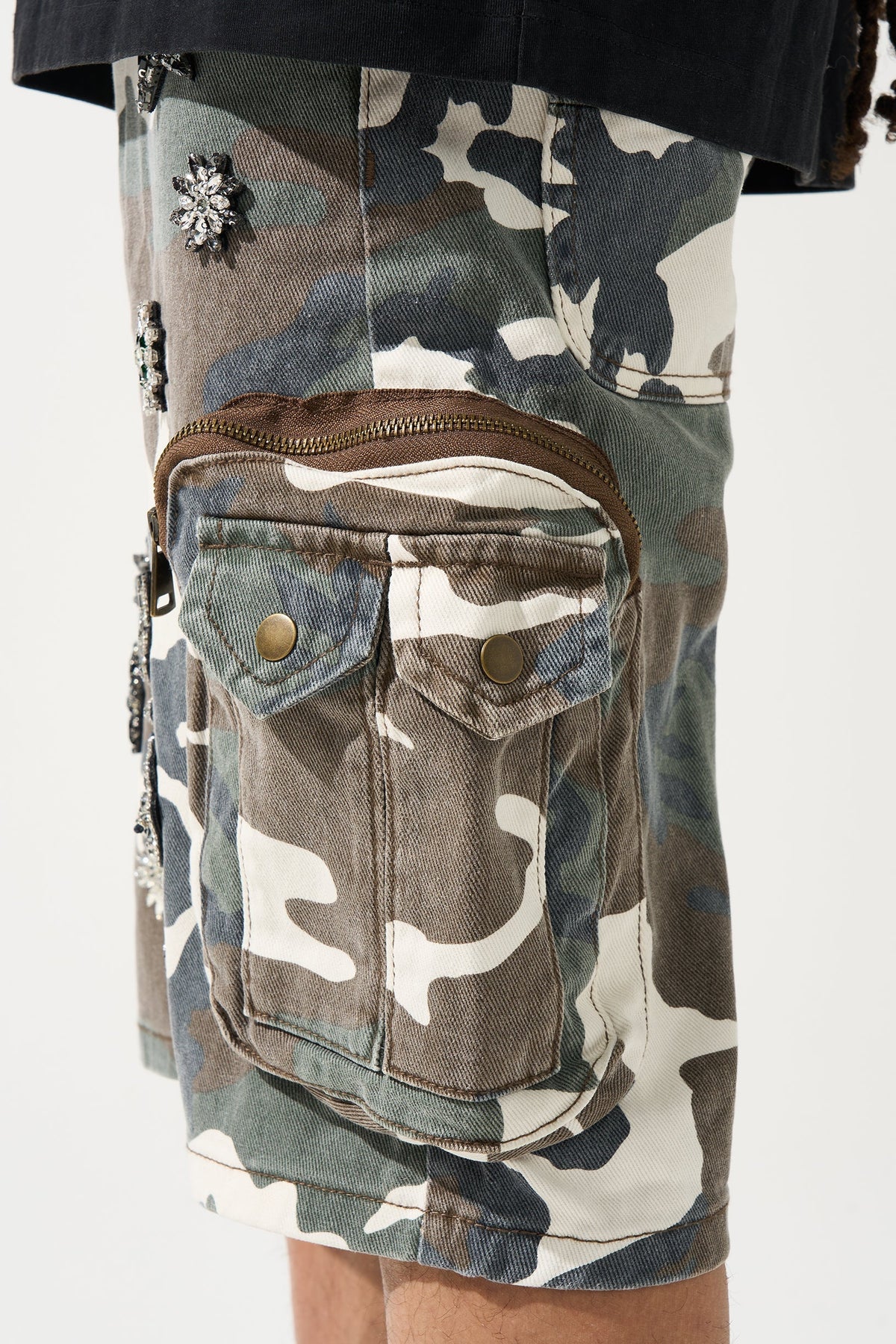 Men's camo cargo shorts close-up of zip hip pocket with brass buttons