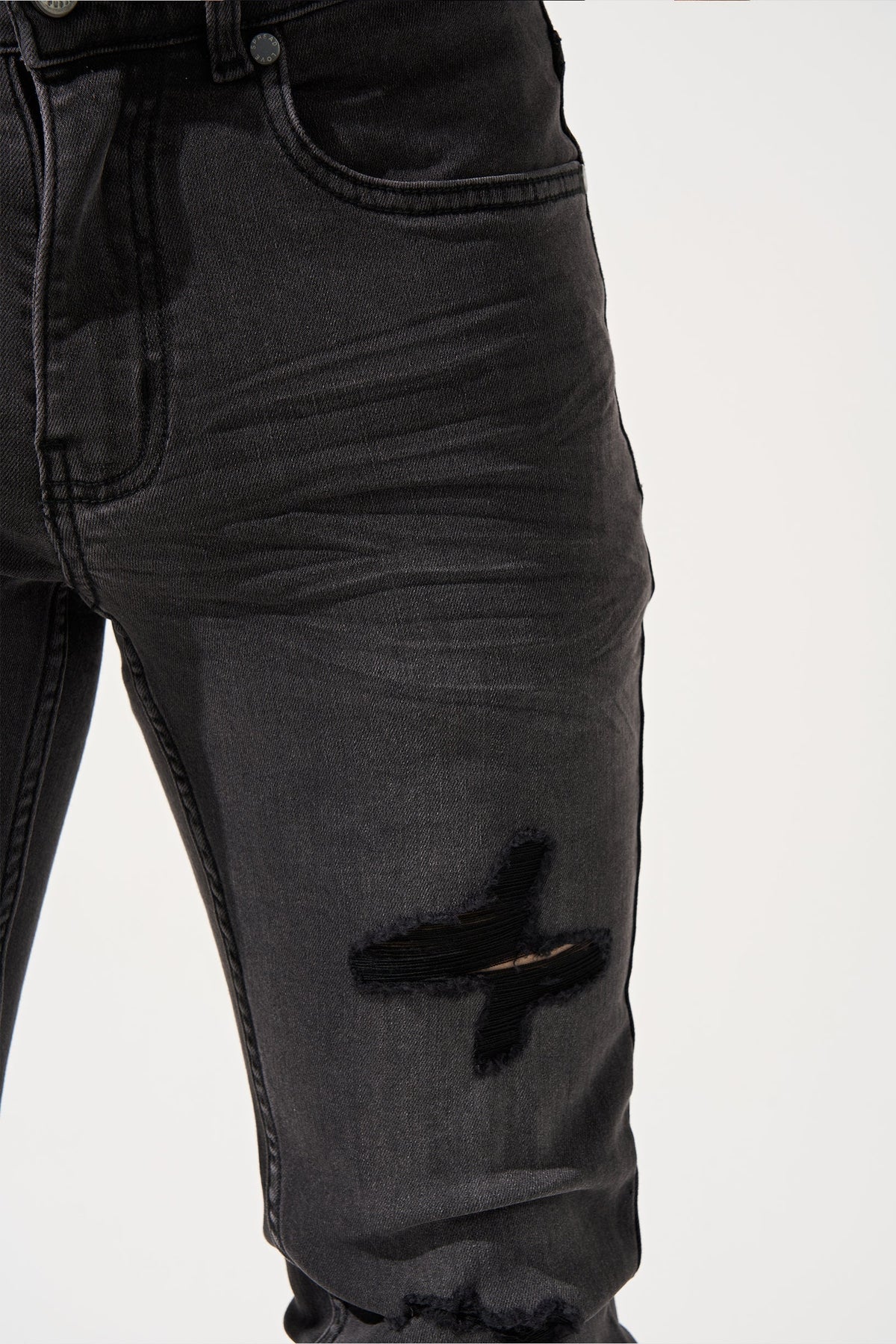 Men's charcoal denim close-up with thigh pocket seam and distressed patch