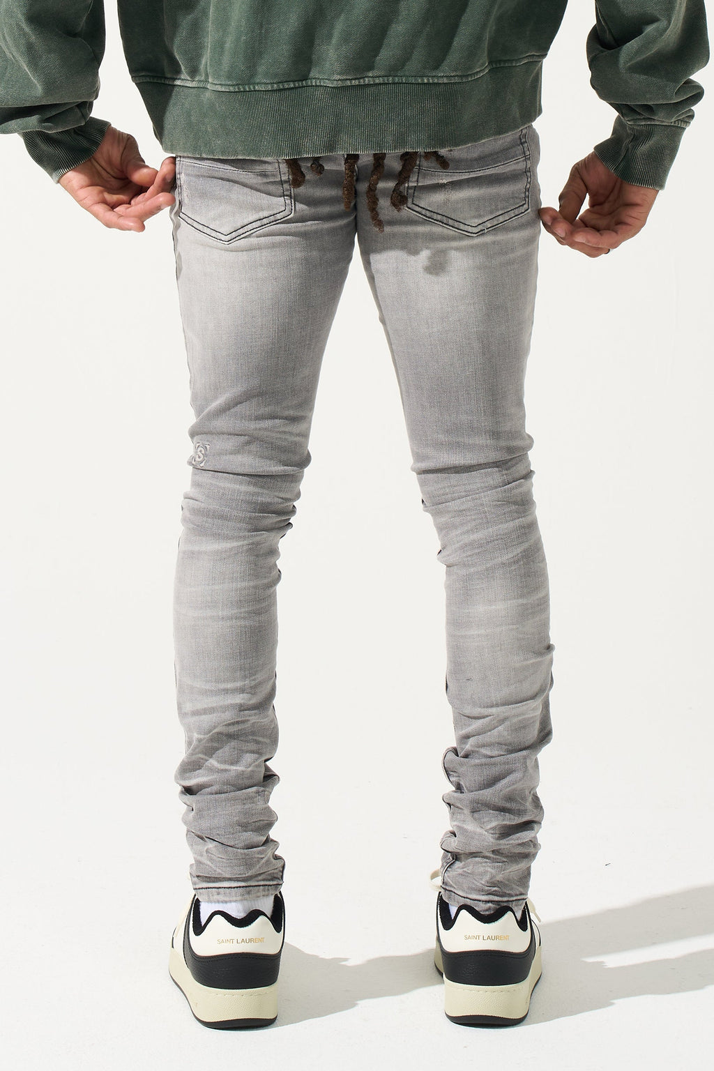 Grey men’s jeans on model from behind, back pockets and ruched legs