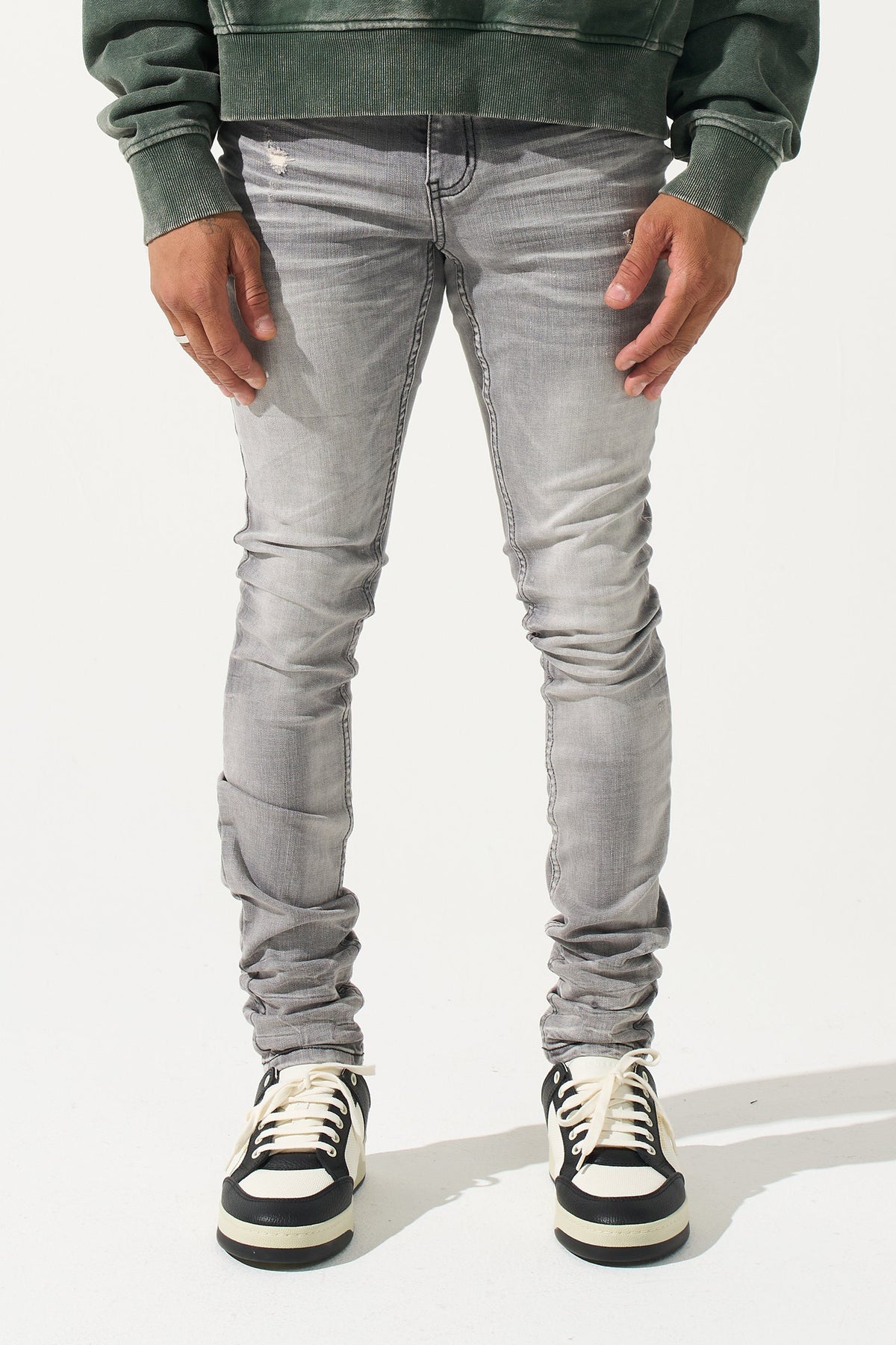 Grey men’s jeans on model, front view with ruched knees and sneakers