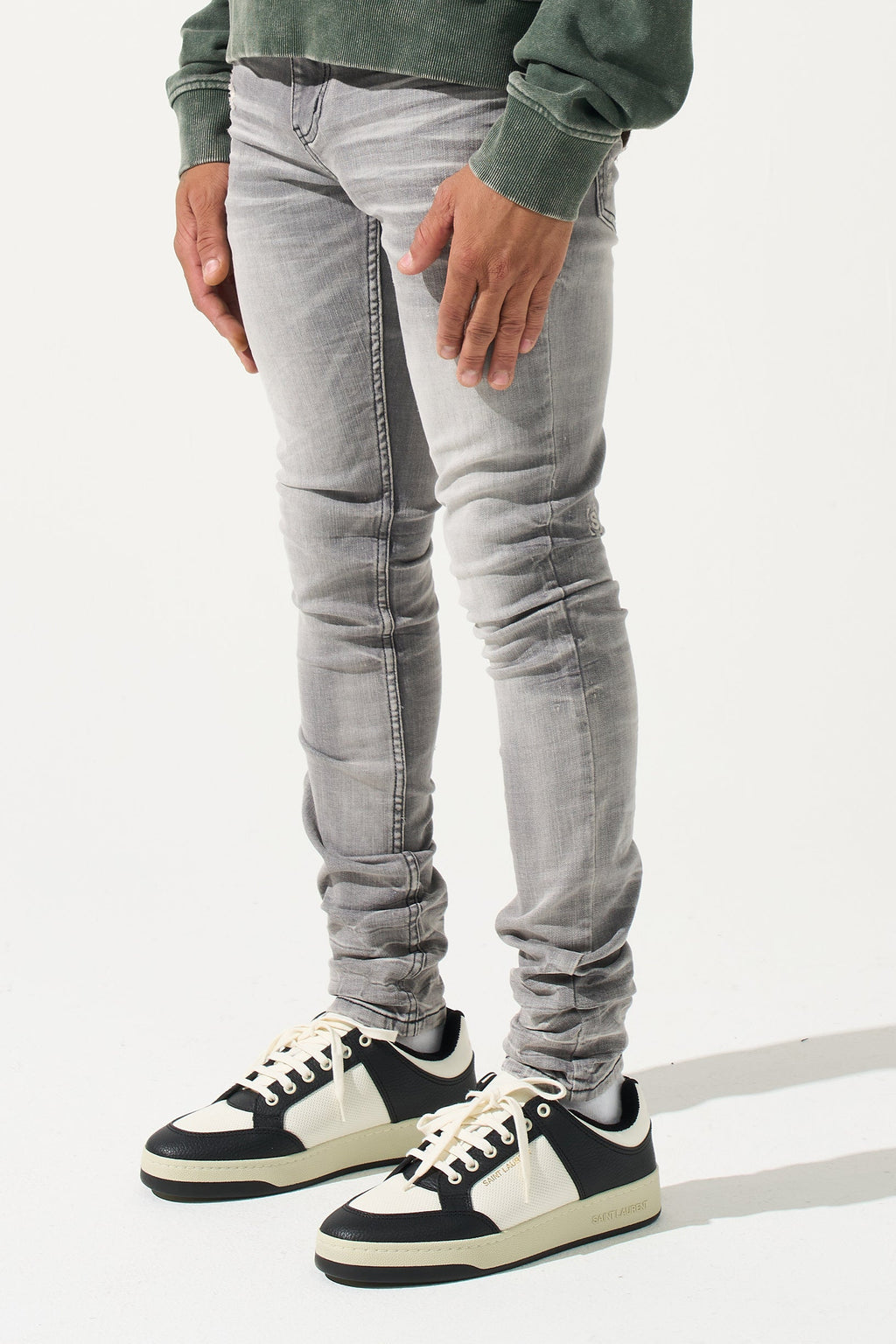 Grey men’s jeans, side view, ruched knee detailing and black sneakers