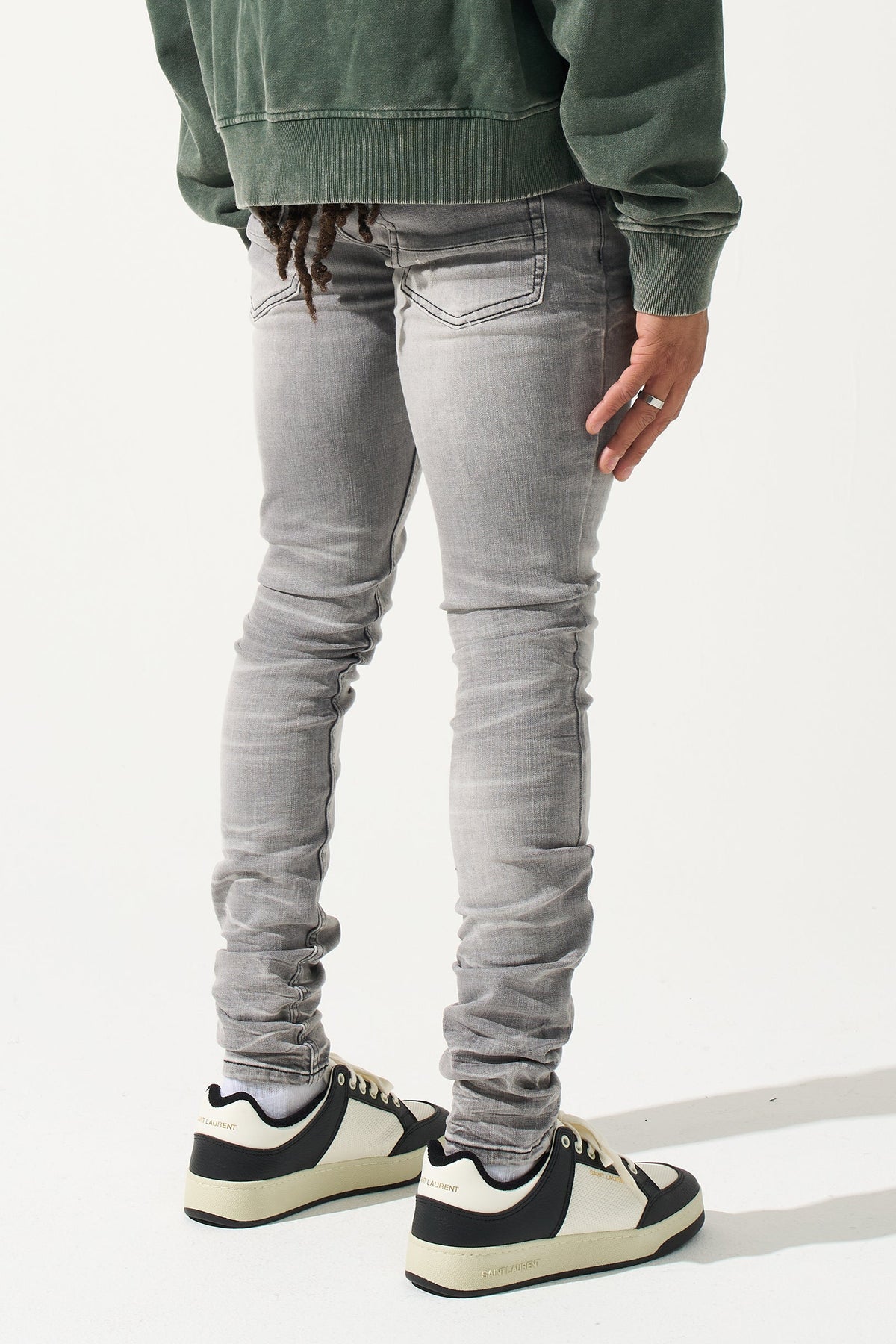 Grey men’s jeans with back pocket and ruched leg seams, plus sneakers