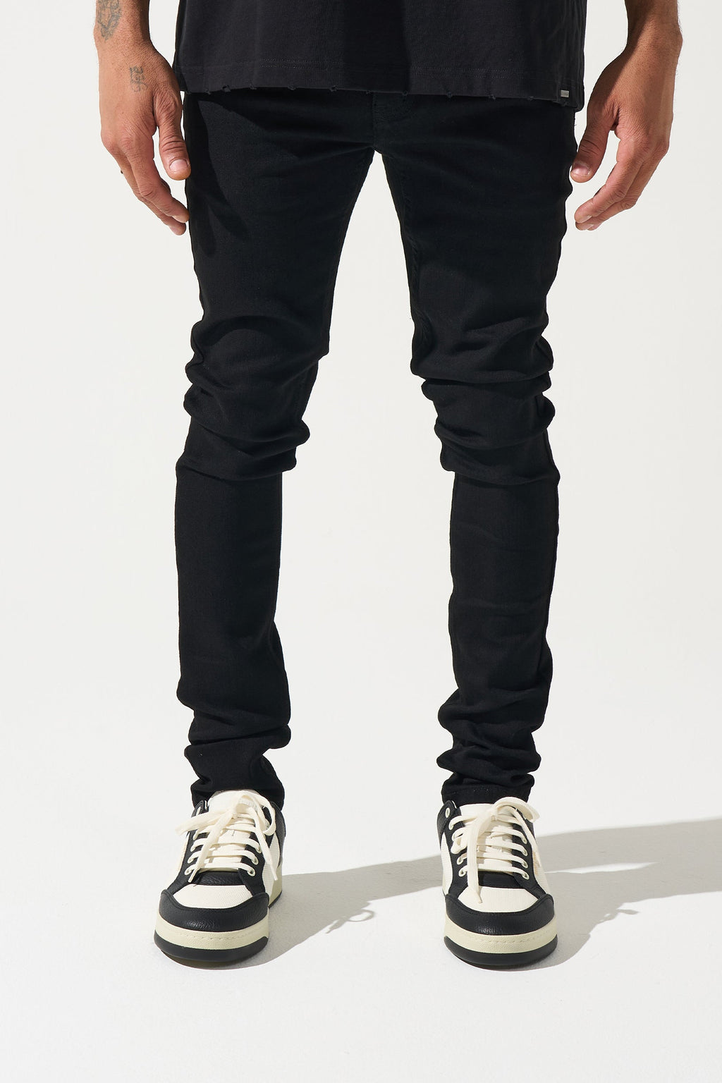Men's black slim-fit jeans with ruched knee seams and tapered legs