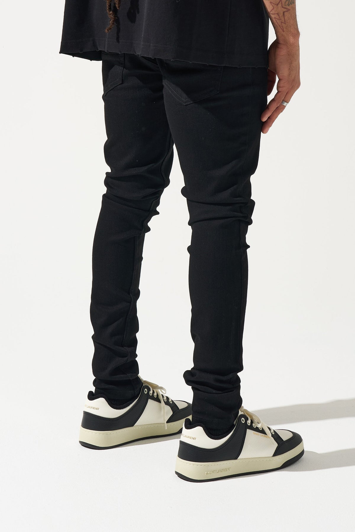 Men's black tapered jeans with diagonal fold detail at the knee